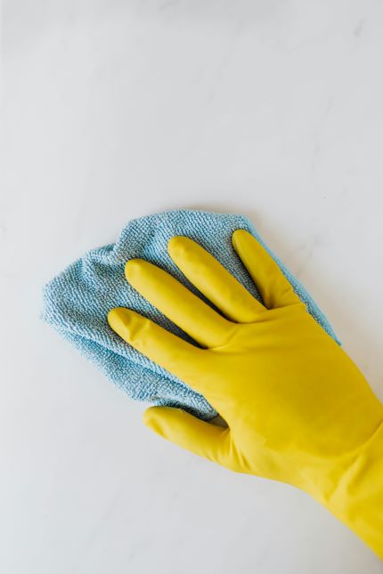 Professional Cleaner in Rubber Glovers wiping with microfiber towel